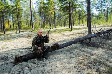 Tüfek ve wildfowls ile oturan avcı. Çalıhorozu avcılık.