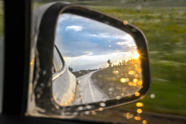 Sunset in the rerview mirror. Sunset Behind. Car and sunlight reflection. Wet glass after the rain.