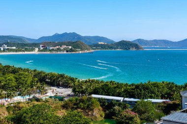Sanya, Hainan, Çin - 20 Şubat 2020: Güney Çin 'deki Dadonghai Körfezi kıyısında turkuaz denizi, dağlar, plaj, jet ski, motorlu tekne ve paraşütleri temizlemek için otelden görüş.