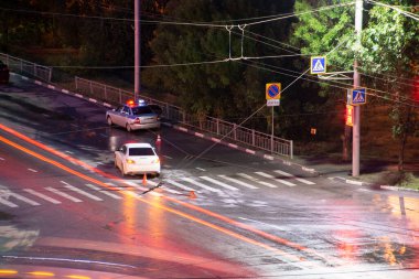 Gece kavşakta, sürücü ihlal ve bir yaya devirdi. Polis bir trafik kazası başlattı. Trafik ihlali. Acil yanıp sönen ışıkları ile polis müfettişi araba.