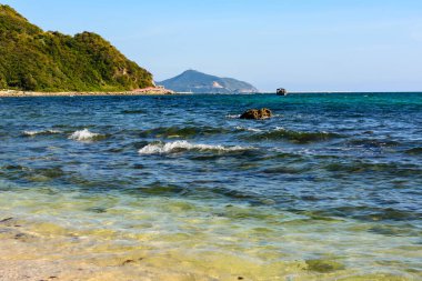 Güneşli bir gün, kum, turkuaz açık deniz, Güney Çin Denizi 'ndeki Xiaodonghai Körfezi kıyısındaki mercan resifleri. Sanya, Hainan Adası, Çin. Doğa Manzarası.