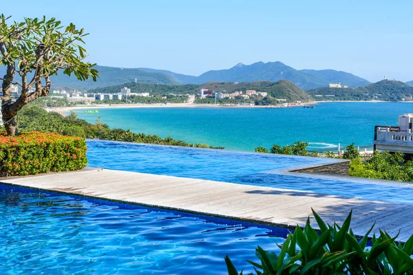 Sanya, Hainan, Çin - 20 Şubat 2020: Güney Çin 'deki Dadonghai Körfezi kıyısında turkuaz denizi, dağlar, plaj, jet ski, motorlu tekne ve paraşütleri temizlemek için otelden görüş.
