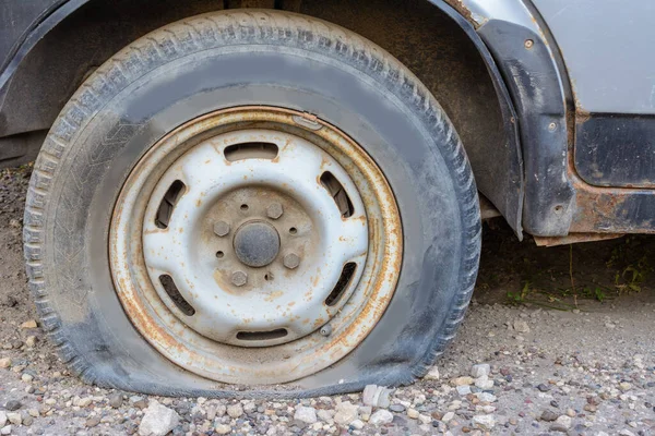 特写镜头损坏轮胎 汽车轮胎的轮子漏气了 扁平的轮胎等待修理 在停车场被弃置的汽车 — 图库照片