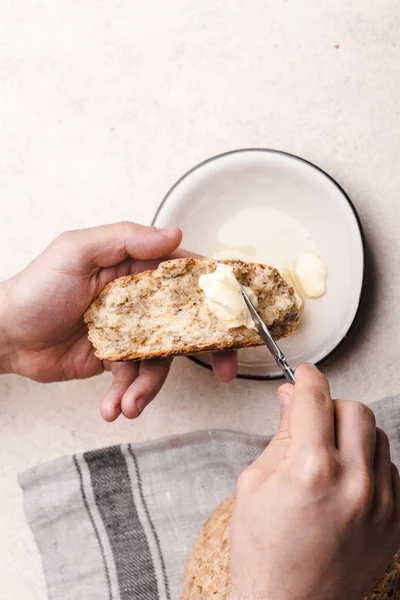 Руки, намазывающие масло на хлеб — стоковое фото