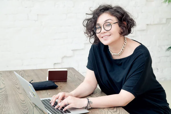 Усміхнена жінка працює на ноутбуці — стокове фото