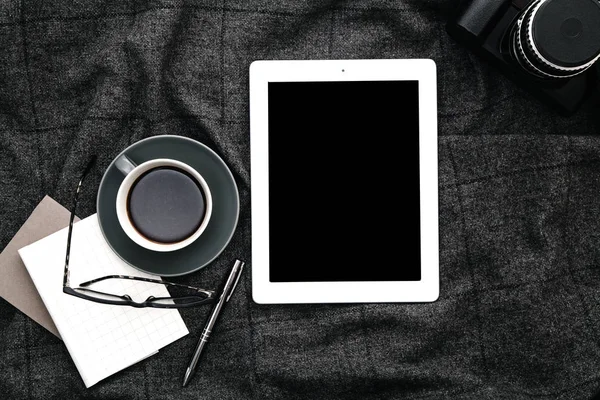 Tablet and coffee on gray woolen plaid