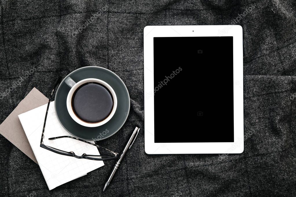 Tablet and coffee on gray woolen plaid