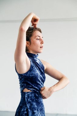 Genç kadın oyuncusu çağdaş dans öğeleri beyaz ferah çatı içinde pratik. Doğal ışık. Dikey kompozisyon, kopya alanı.