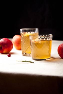 Elma siyah arka plan üzerine iki vintage gözlüklü. Noel içecek konsepti. İki kırmızı elma ve biberiye delikanlı bir kenara. Sıcak arka ışık. Dikey kompozisyon.