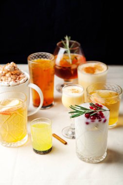 Çeşitli kış kokteyller kümesi: mulled şarap, yumurta likörü, limoncello, eski moda, Hindistan cevizi margarita. Siyah arka plan, beyaz keten masa örtüsü. Dikey kompozisyon. Kopya alanı.