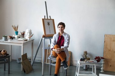 Kadın sanatçı onun geniş beyaz Studio suluboya ile çalışma. Doğal ışık. Yaratıcılık kavramı açıklanması. Yatay kompozisyon.