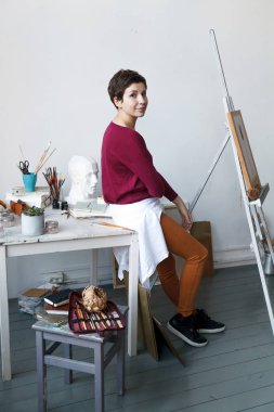 Kadın sanatçı onun geniş beyaz Studio suluboya ile çalışma. Doğal ışık. Yaratıcılık kavramı açıklanması. Dikey kompozisyon.