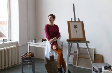 Kadın sanatçı onun geniş beyaz Studio suluboya ile çalışma. Doğal ışık. Yaratıcılık kavramı açıklanması. Yatay kompozisyon.