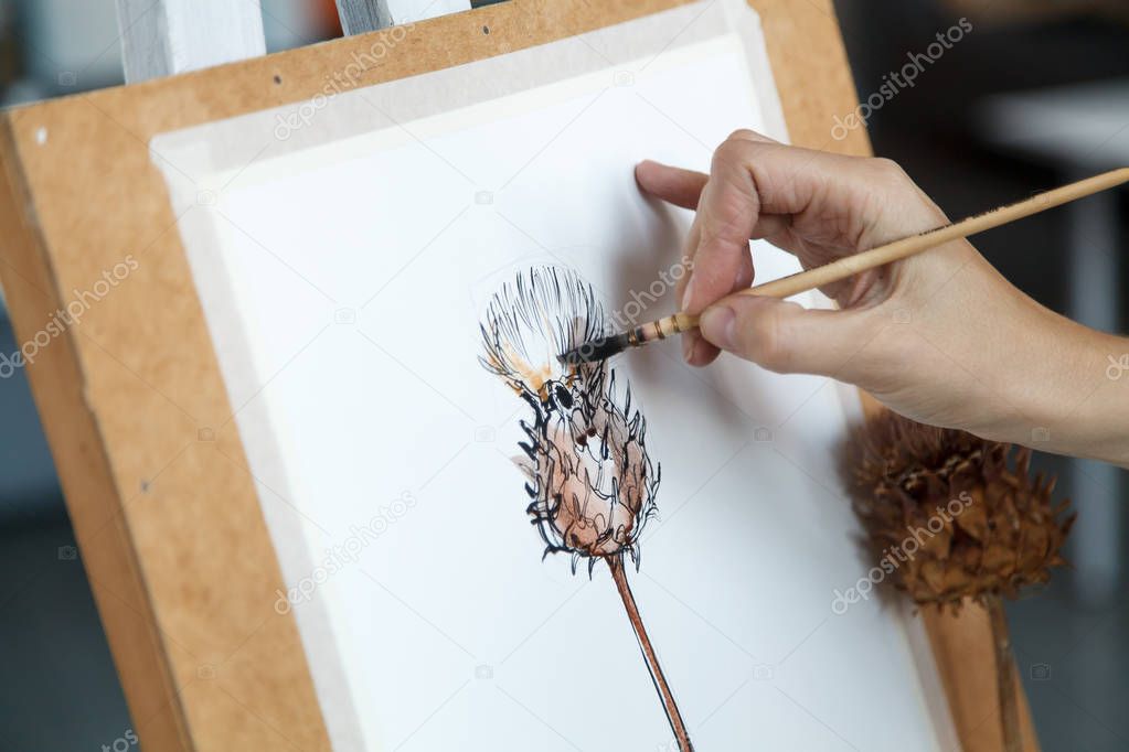 Female artist creating watercolor image of decorative artichoke. Natural lighting. Disclosure of creativity concept. Horizontal composition.