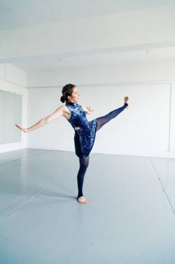 Genç kadın oyuncusu çağdaş dans öğeleri beyaz ferah çatı içinde pratik. Doğal ışık. Dikey kompozisyon, kopya alanı.
