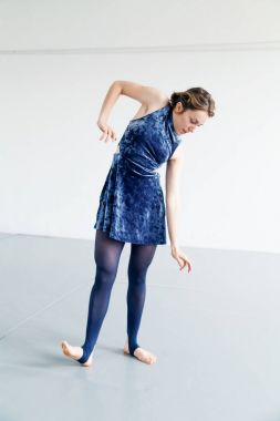 Genç kadın oyuncusu çağdaş dans öğeleri beyaz ferah çatı içinde pratik. Doğal ışık. Dikey kompozisyon, kopya alanı.