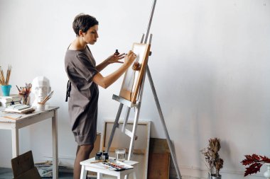 Kadın sanatçı onun geniş beyaz Studio suluboya ile çalışma. Doğal ışık. Yaratıcılık kavramı açıklanması. Yatay kompozisyon.