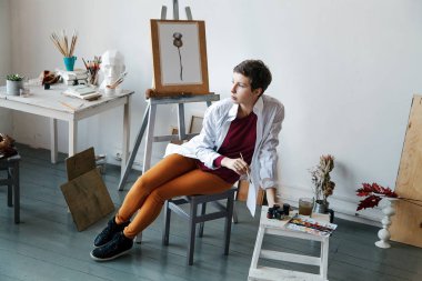 Kadın sanatçı onun geniş beyaz Studio suluboya ile çalışma. Doğal ışık. Yaratıcılık kavramı açıklanması. Yatay kompozisyon.