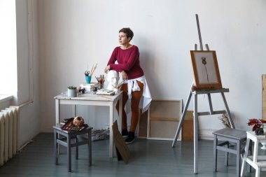 Kadın sanatçı onun geniş beyaz Studio suluboya ile çalışma. Doğal ışık. Yaratıcılık kavramı açıklanması. Yatay kompozisyon.