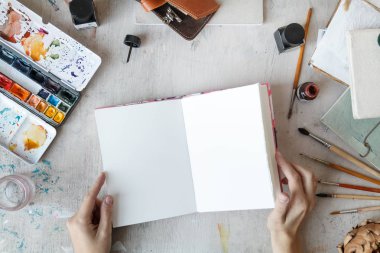 Serbest Sanatçı açılan sketchbook üstten görünüm ile işyeri. Düz yatıyordu kompozisyon kopya alanı ile. Doğal ışık. 