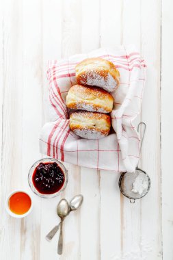 Beyaz ahşap zemin üzerinde bir kutu içinde düzenlenmiş jöle ile üç sufganiyot çörek ayarla. Dikey kompozisyon.