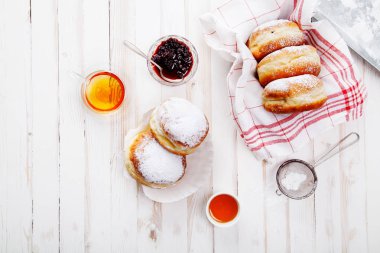 Beyaz ahşap zemin üzerinde bir kutu içinde düzenlenmiş jöle ile üç sufganiyot çörek ayarla. Yatay kompozisyon.