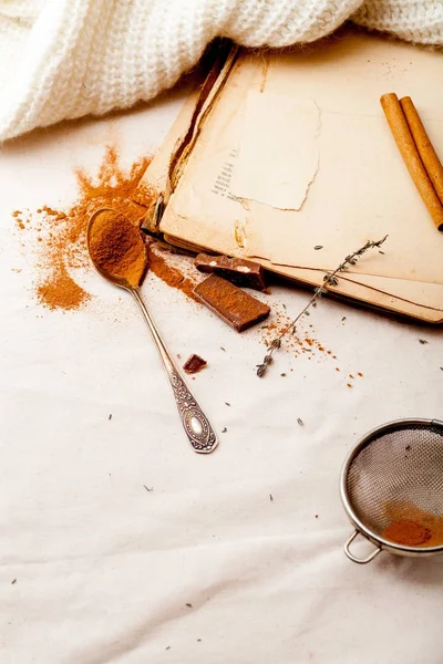 Tea spoon with spilled cocoa powder on linen background with old-fashioned cookbooks aside. Top view. Vintage kitchen concept.
