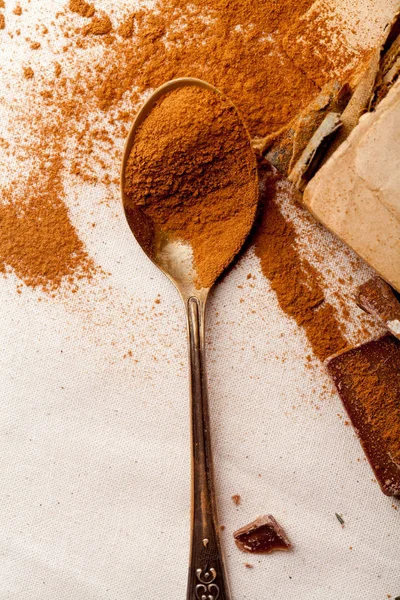 Tea spoon with spilled cocoa powder on linen background with old-fashioned cookbooks aside. Top view. Vintage kitchen concept. Macro view.