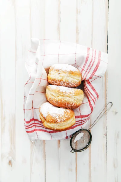 Beyaz ahşap zemin üzerinde bir kutu içinde düzenlenmiş jöle ile üç sufganiyot çörek ayarla. Dikey kompozisyon.