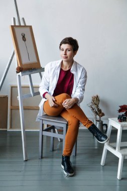 Kadın sanatçı onun geniş beyaz Studio suluboya ile çalışma. Doğal ışık. Yaratıcılık kavramı açıklanması. Dikey kompozisyon.