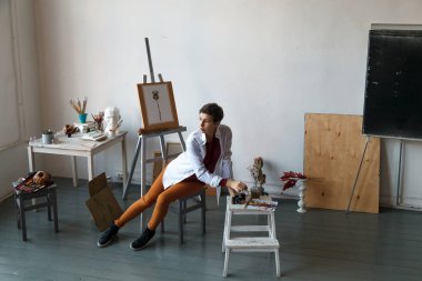 Kadın sanatçı onun geniş beyaz Studio suluboya ile çalışma. Doğal ışık. Yaratıcılık kavramı açıklanması. Yatay kompozisyon.