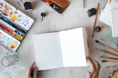 Serbest Sanatçı açılan sketchbook üstten görünüm ile işyeri. Düz yatıyordu kompozisyon kopya alanı ile. Doğal ışık. 