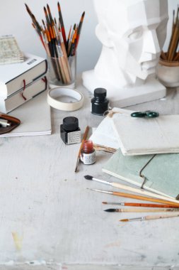 İçişleri Resim Studio serbest sanatçı. Alçı şişe masanın üzerinde sketchbooks ile baş, fırçalar, pencills, mürekkep ve boya. Serbest Sanatçı yaşam tarzı kavramı. Kopya alanı