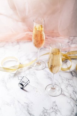İki gözlük ile mermer zemin üzerine şampanya flüt. Pembe şeffaf kumaş. Yumuşak ışık