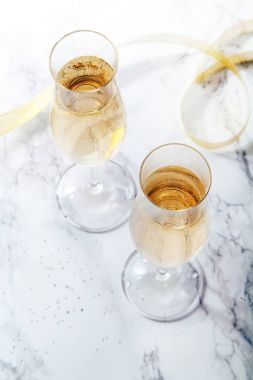 İki gözlük ile mermer zemin üzerine şampanya flüt. Doğrudan güneş ışığı ile ağır gölgeler. Dikey kompozisyon