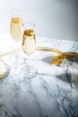 İki gözlük ile mermer zemin üzerine şampanya flüt. Doğrudan güneş ışığı ile ağır gölgeler. Dikey kompozisyon