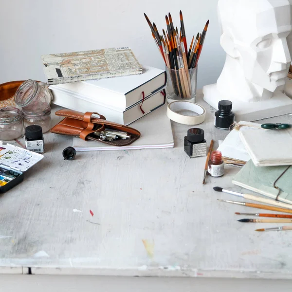 İçişleri Resim Studio serbest sanatçı. Alçı şişe masanın üzerinde sketchbooks ile baş, fırçalar, pencills, mürekkep ve boya. Serbest Sanatçı yaşam tarzı kavramı. Kare kompozisyon. Kopya alanı