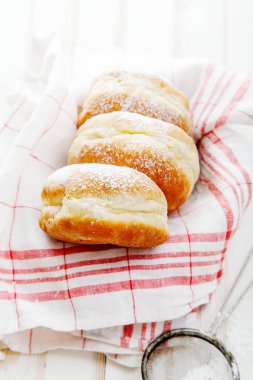 Beyaz ahşap zemin üzerinde bir kutu içinde düzenlenmiş jöle ile üç sufganiyot çörek ayarla. Dikey kompozisyon. Makro görünümü.