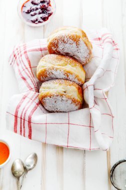 Beyaz ahşap zemin üzerinde bir kutu içinde düzenlenmiş jöle ile üç sufganiyot çörek ayarla. Dikey kompozisyon.