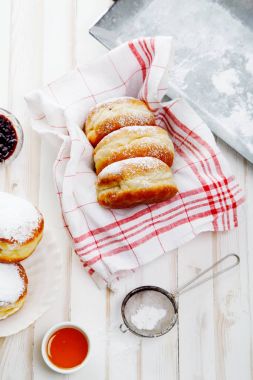 Beyaz ahşap zemin üzerinde bir kutu içinde düzenlenmiş jöle ile üç sufganiyot çörek ayarla. Dikey kompozisyon.