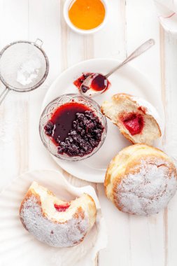 Çay saati ile festival sufganiyot donut jöle ile dolu ve pudra şekeri ile kaplı. Beyaz ahşap zemin, parlak ışık. Görünümü kapatın.
