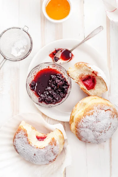 Çay saati ile festival sufganiyot donut jöle ile dolu ve pudra şekeri ile kaplı. Beyaz ahşap zemin, parlak ışık. Görünümü kapatın.