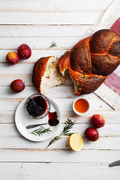 Traditional jewish bread brown challah on white wooden background with fruits and honey. Rustic concept. Copy space