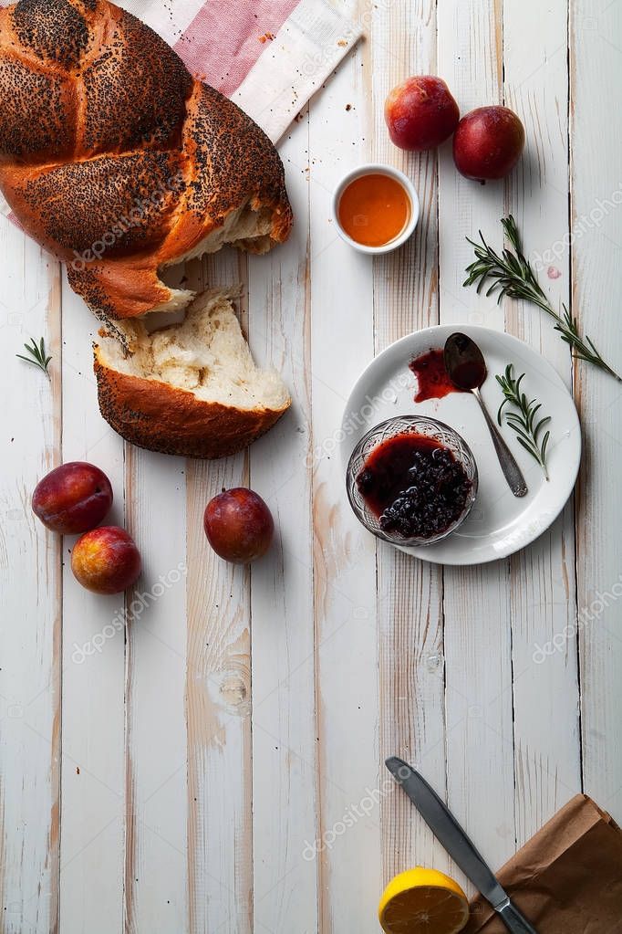 Pan tradicional judío marrón jalá sobre fondo de madera blanca con frutas y miel. Concepto