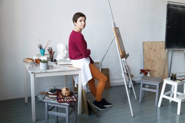 Kadın sanatçı onun geniş beyaz Studio suluboya ile çalışma. Doğal ışık. Yaratıcılık kavramı açıklanması. Yatay kompozisyon.