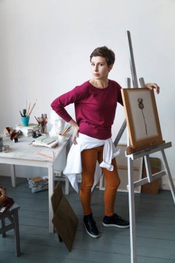 Kadın sanatçı onun geniş beyaz Studio suluboya ile çalışma. Doğal ışık. Yaratıcılık kavramı açıklanması. Dikey kompozisyon.