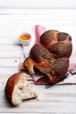 Geleneksel Yahudi ekmeği kahverengi challah beyaz ahşap zemin üzerinde meyve ve bal ile. Kaba bir kavram. Kapat..
