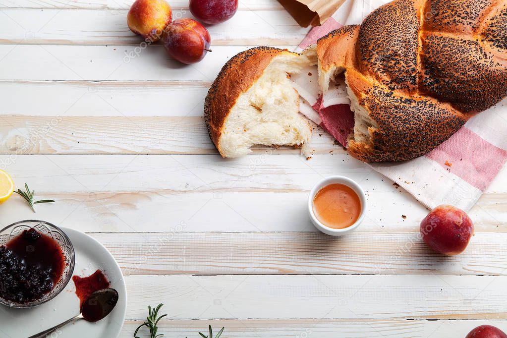 Pan tradicional judío marrón jalá sobre fondo de madera blanca con frutas y miel. Concepto