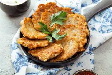 Patates Latkeler geleneksel Yahudi krep ekşi krema, maydanoz, kuru kırmızı pul biber ve nane sosu ile. Arka plan, beyaz mavi çiçekli peçete. Hannukah kutlama yemeği kavramı. Yakın çekim.