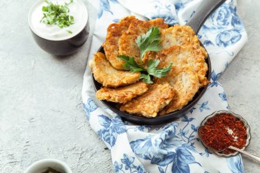 Patates Latkeler geleneksel Yahudi krep ekşi krema, maydanoz, kuru kırmızı pul biber ve nane sosu ile. Arka plan, beyaz mavi çiçekli peçete. Hannukah kutlama yemeği kavramı. Yakın çekim.